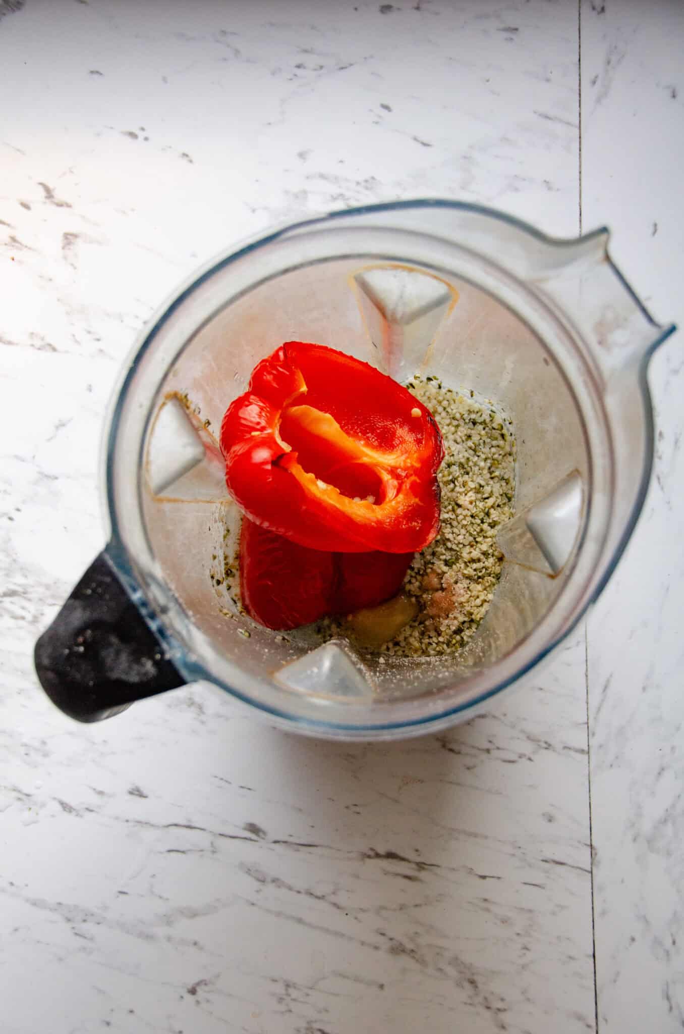 Red pepper in a blender container with hemp hearts honey, sea salt, and water.