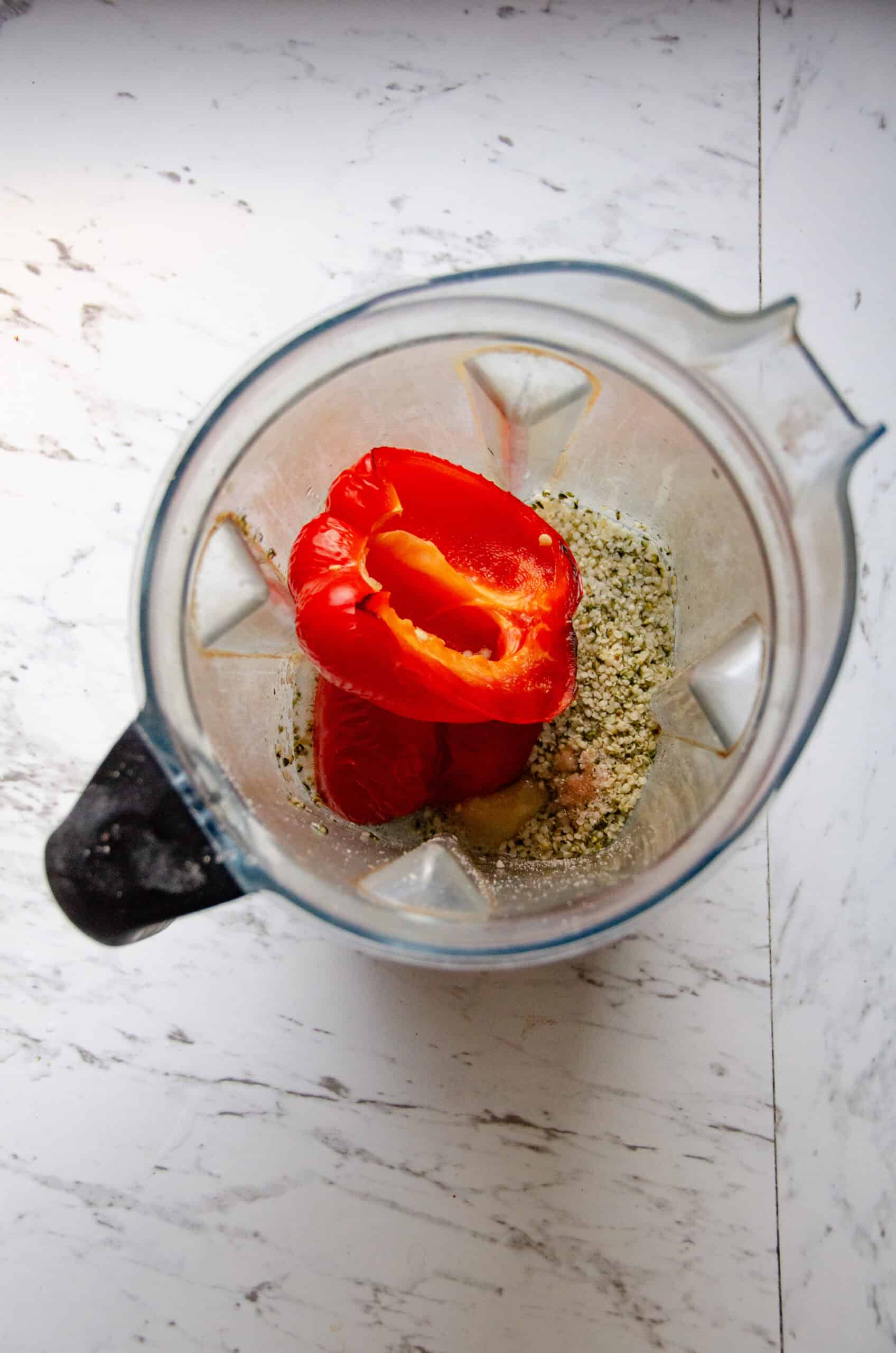 Red pepper in a blender container with hemp hearts honey, sea salt, and water.