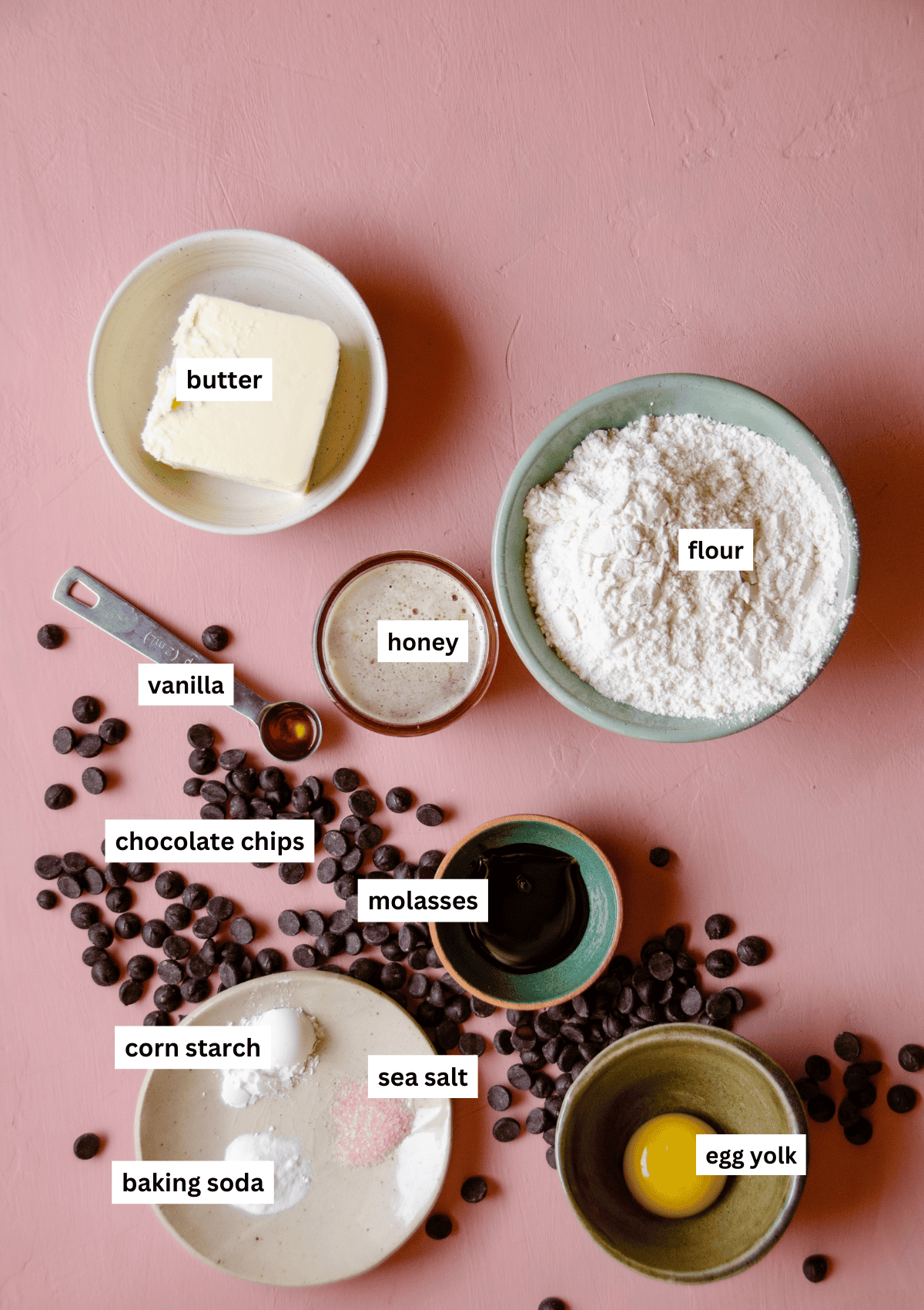 Labelled ingredients needed to make chocolate chip cookies with honey, including butter, flour, honey, vanilla, chocolate chips, molasses, corn starch, baking soda, sea salt, egg yolk.