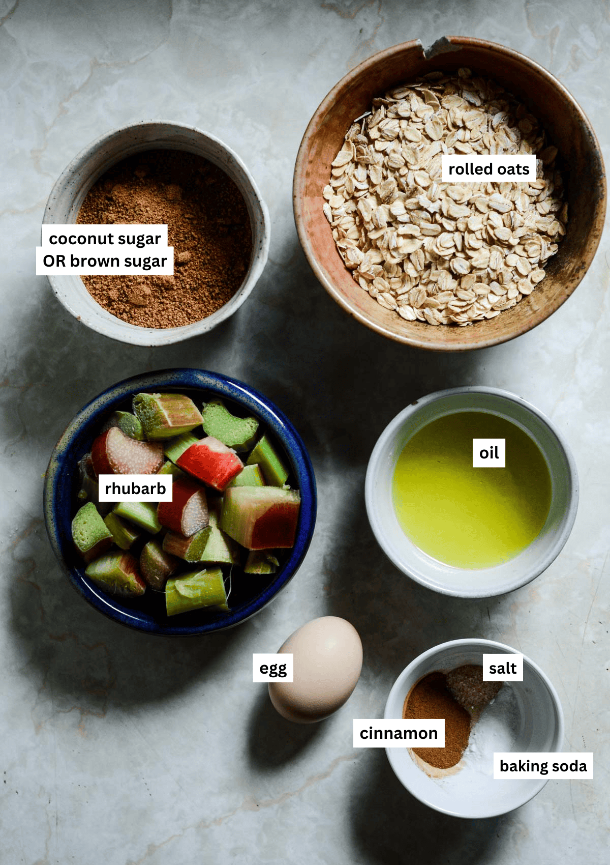 Rhubarb, coconut sugar, rolled oats, oil, egg, baking powder, salt, cinnamon in bowls ready for baking cookies.