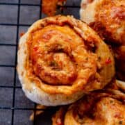 Pizza bun all rolled up and beside others on a cooling rack.