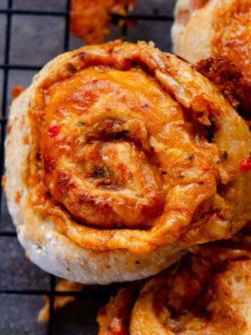 Pizza bun all rolled up and beside others on a cooling rack.