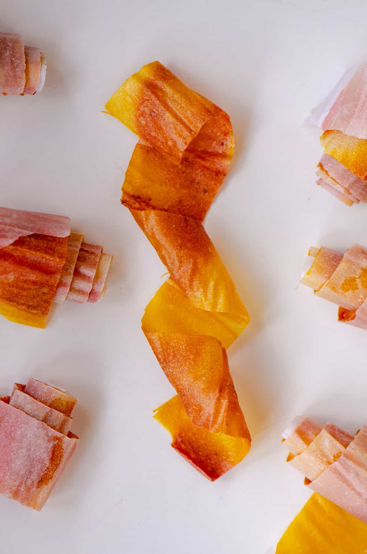 A pink and yellow fruit roll up twisted up.