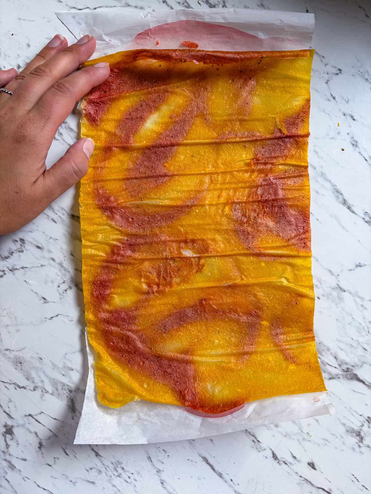 Dried fruit leather stuck to parchment paper.