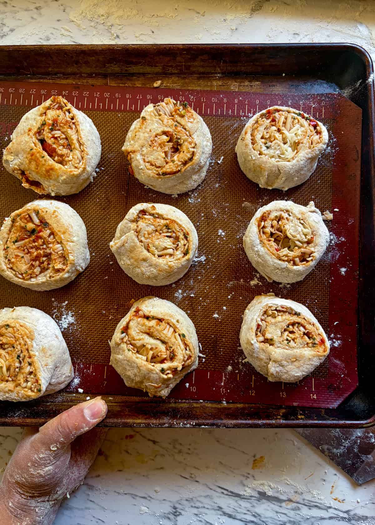 Pizza rolls on a baking pan with space between them.