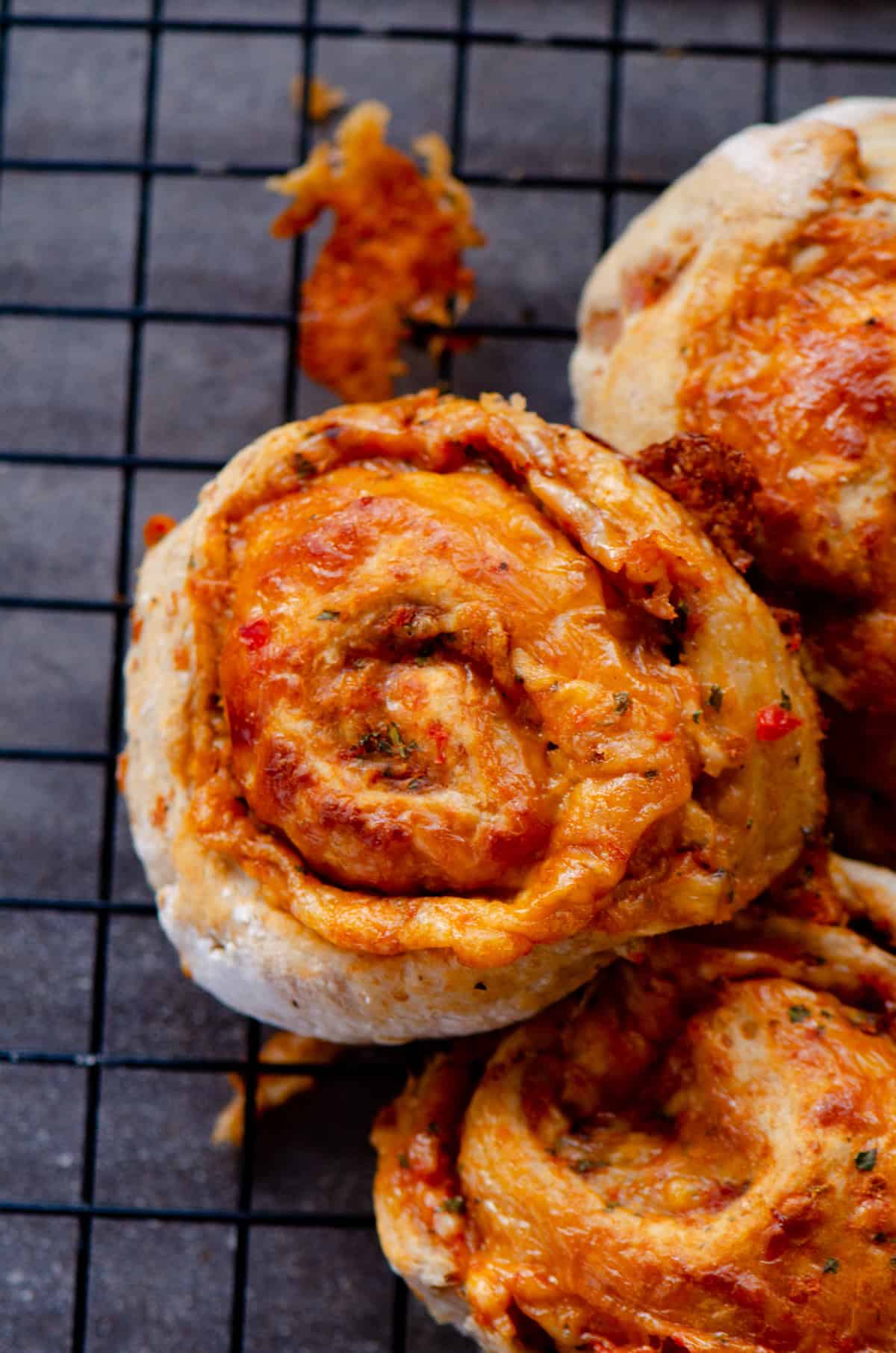 Pizza bun all rolled up and beside others on a cooling rack.