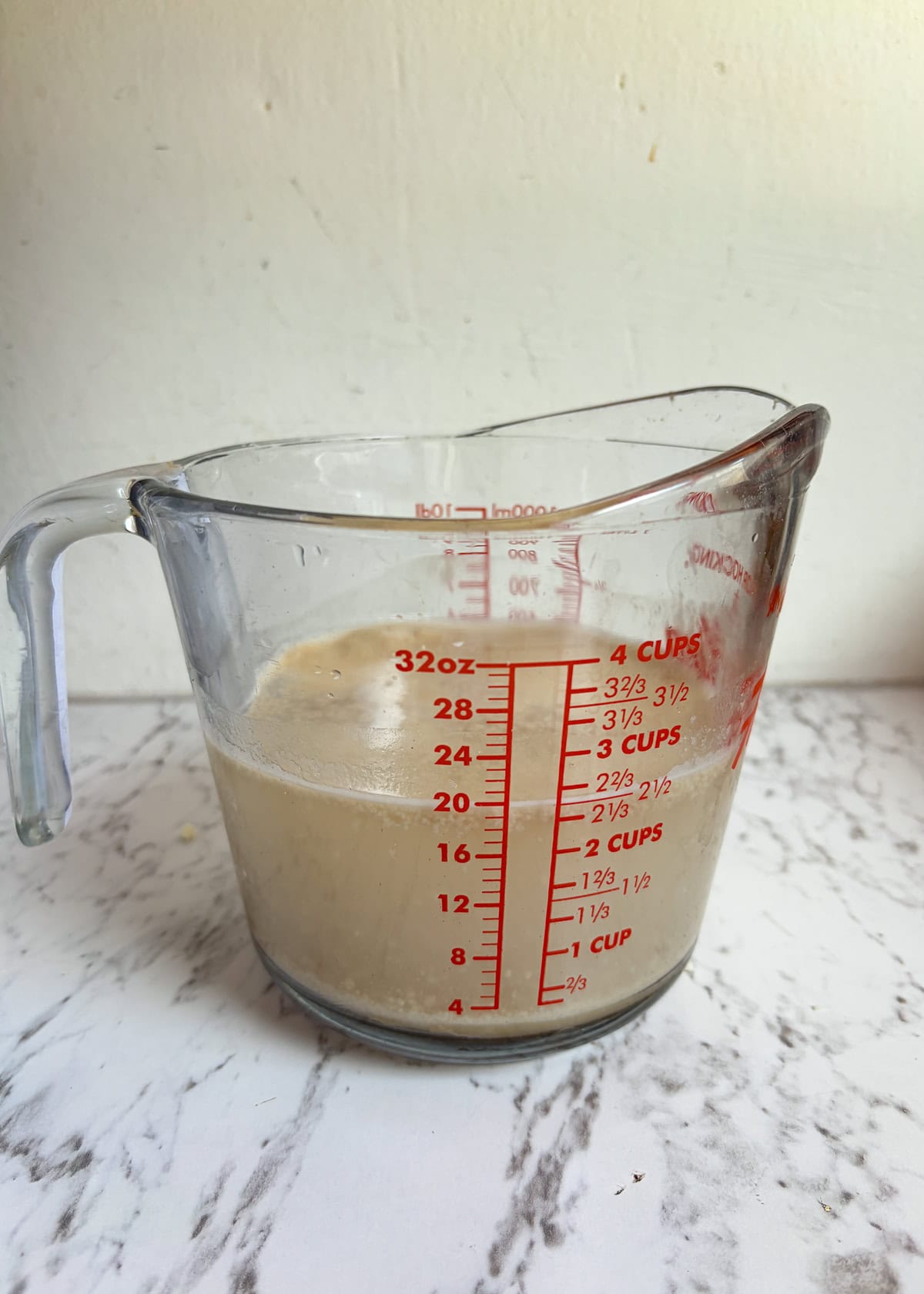 A glass pyrex measuring glass with yeast and water in it.