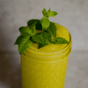 A neon yellow slushie in a jar with fresh mint on top.