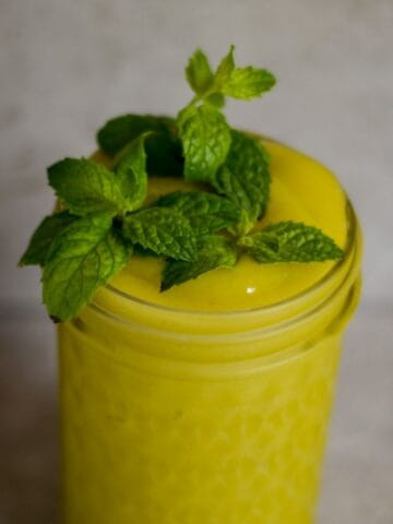 A neon yellow slushie in a jar with fresh mint on top.