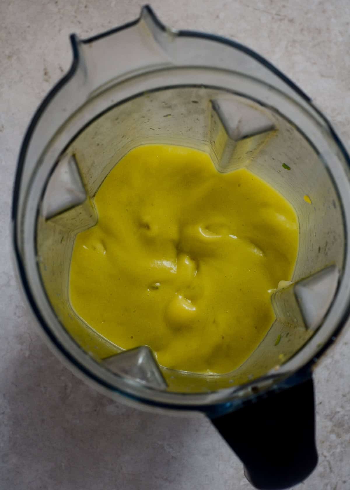 Blended neon yellow drink in the vitamix blender container.