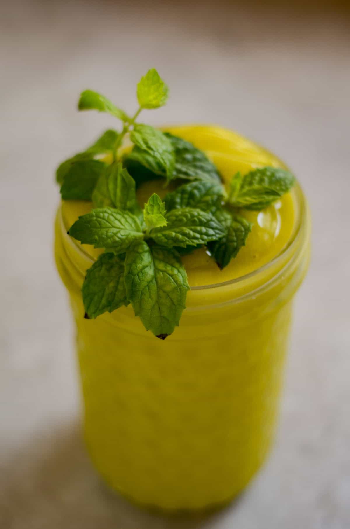 Bright neon yellow slushy with fresh mint on top.