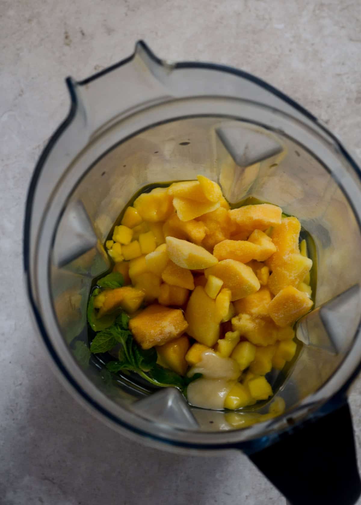 Frozen mango, mint, honey, coconut water, and sea salt in the blender container.