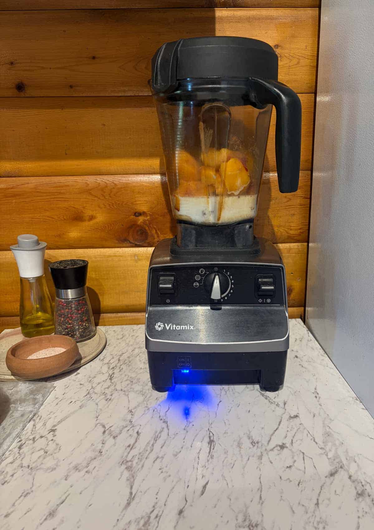 A blender container on the stand ready to be blended with a blue on button.