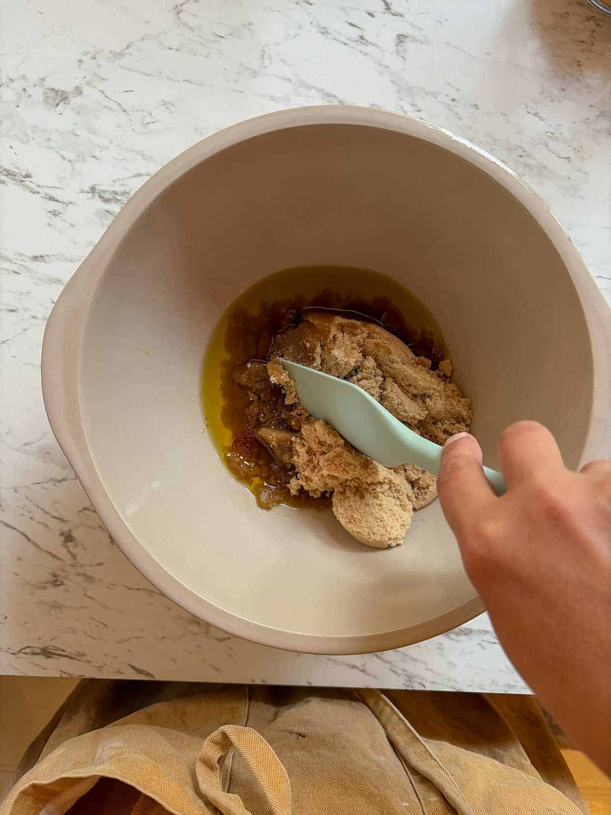 A mixing bowl with brown sugar and olive oil.